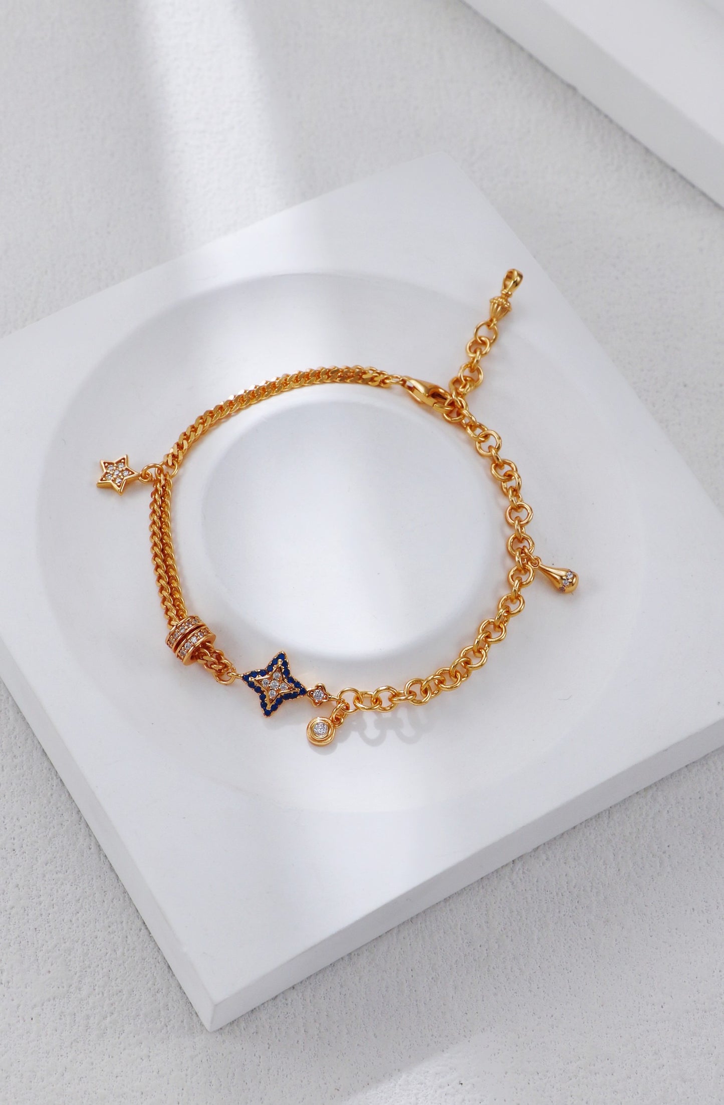 Gold bracelet with star charm on a white surface