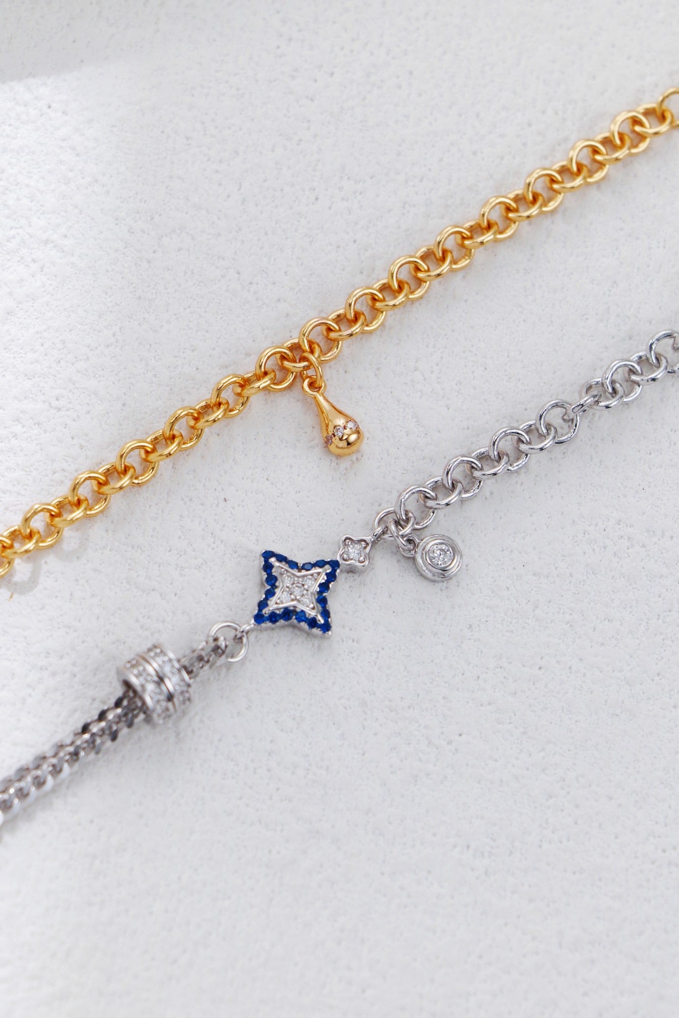 Two gold and silver bracelets with star-shaped charms on a white background