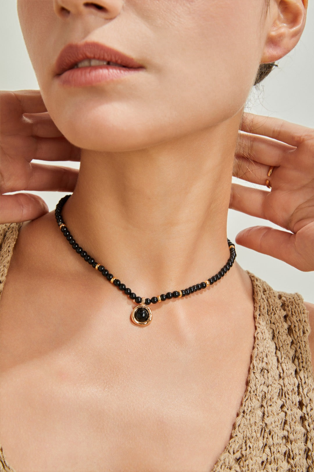 Close-up of a person wearing a black beaded necklace with a gold clasp.