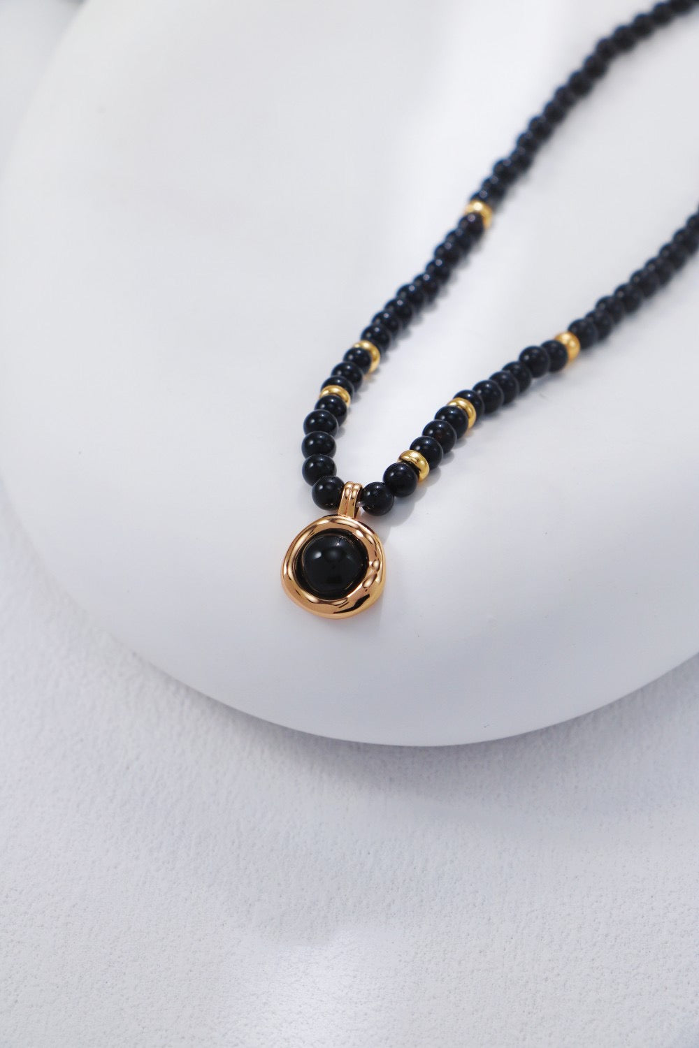 Necklace with black beads and a gold clasp on a white background