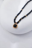 Necklace with black beads and a gold clasp on a white background
