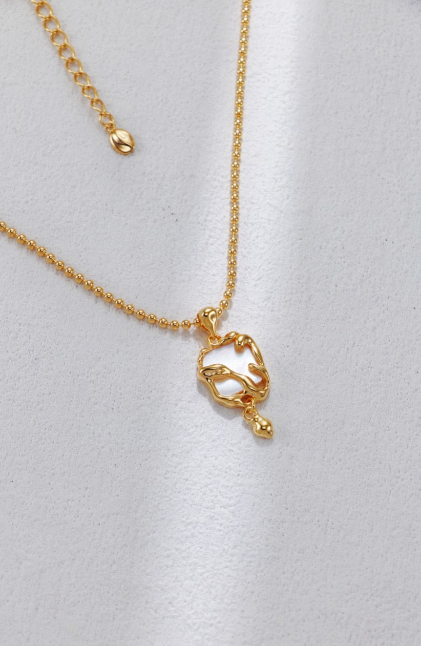Gold necklace with a heart-shaped pendant on a light gray background