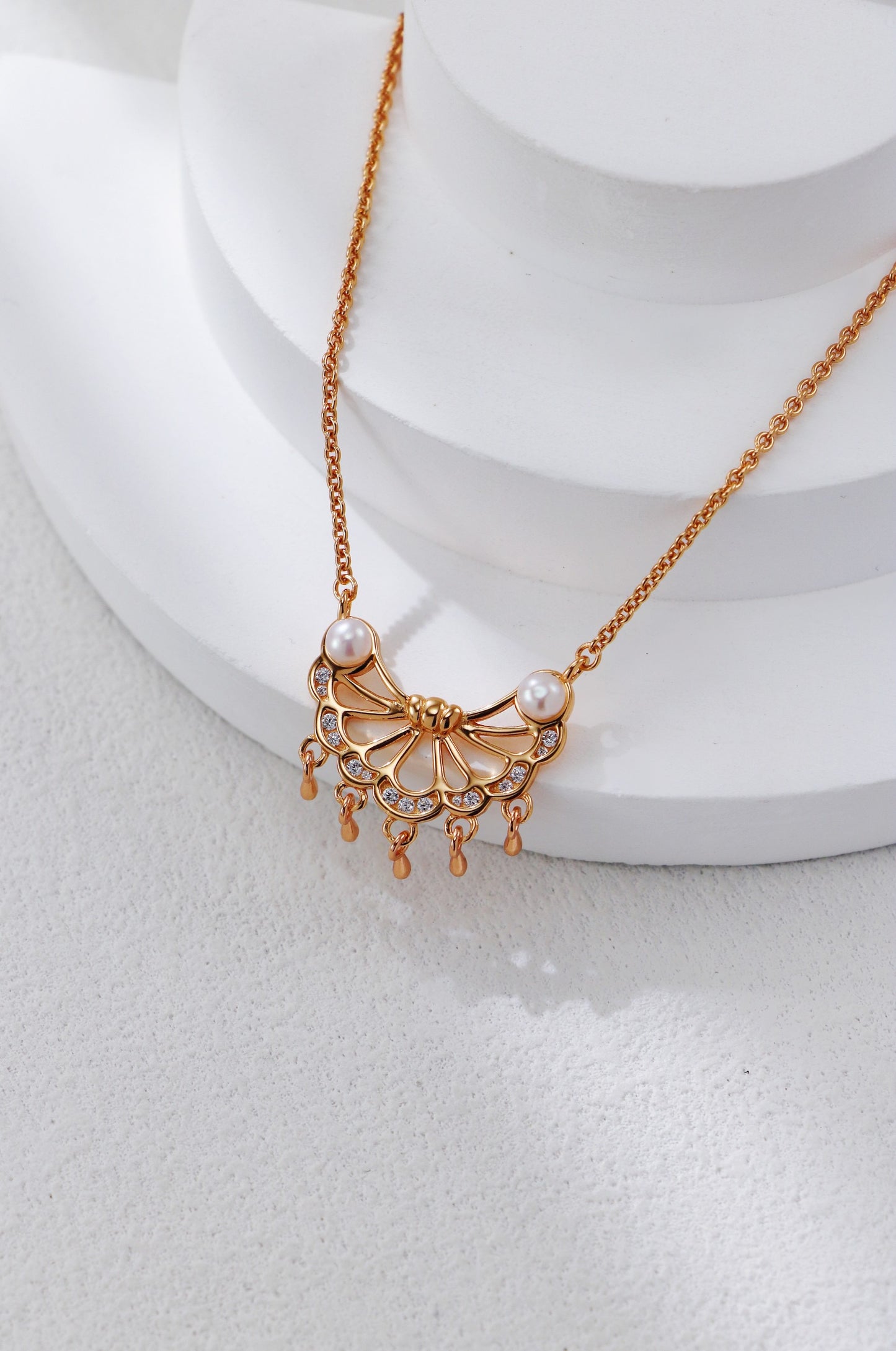 Gold necklace with a decorative pendant on a white surface