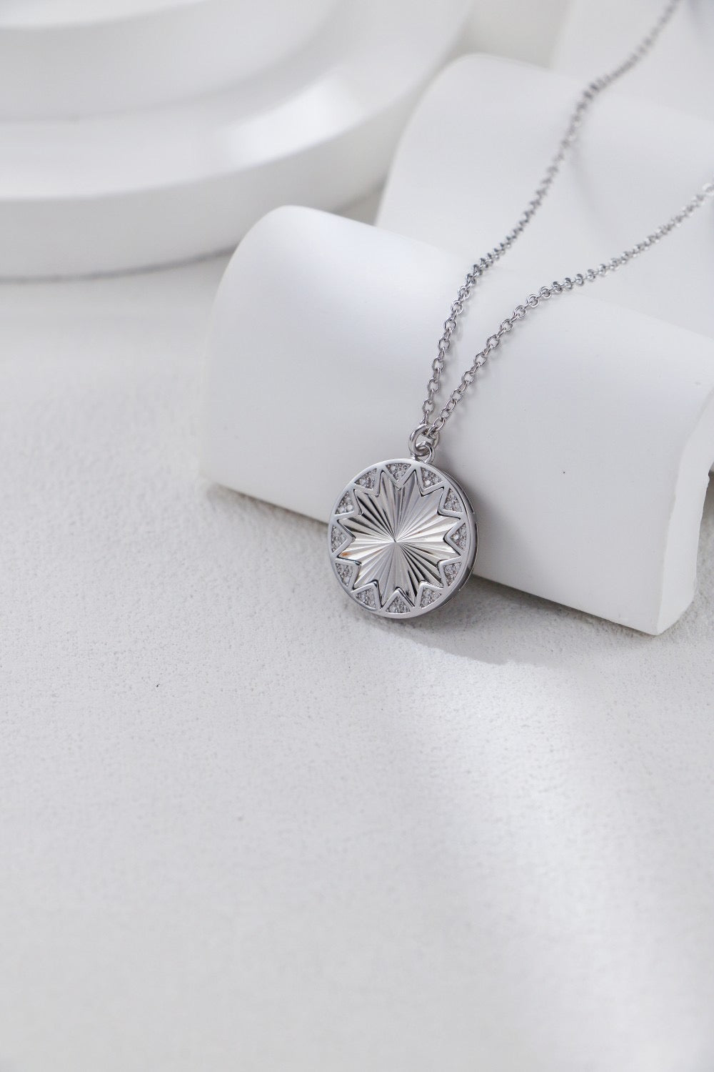 Silver necklace with a round pendant on a white surface