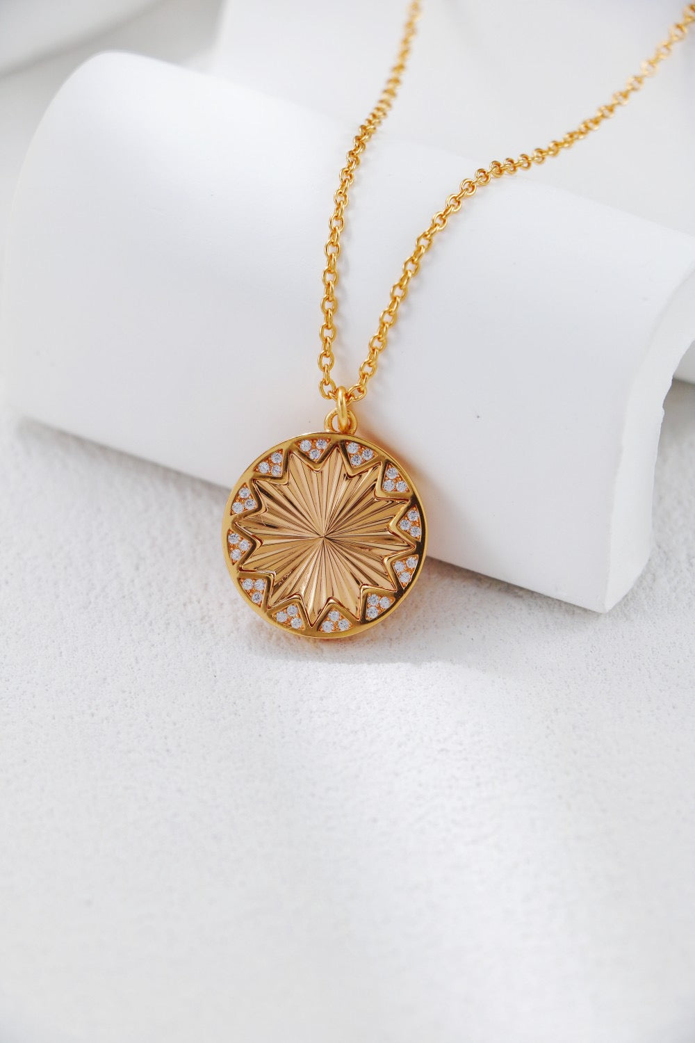 Gold necklace with a detailed pendant on a white surface