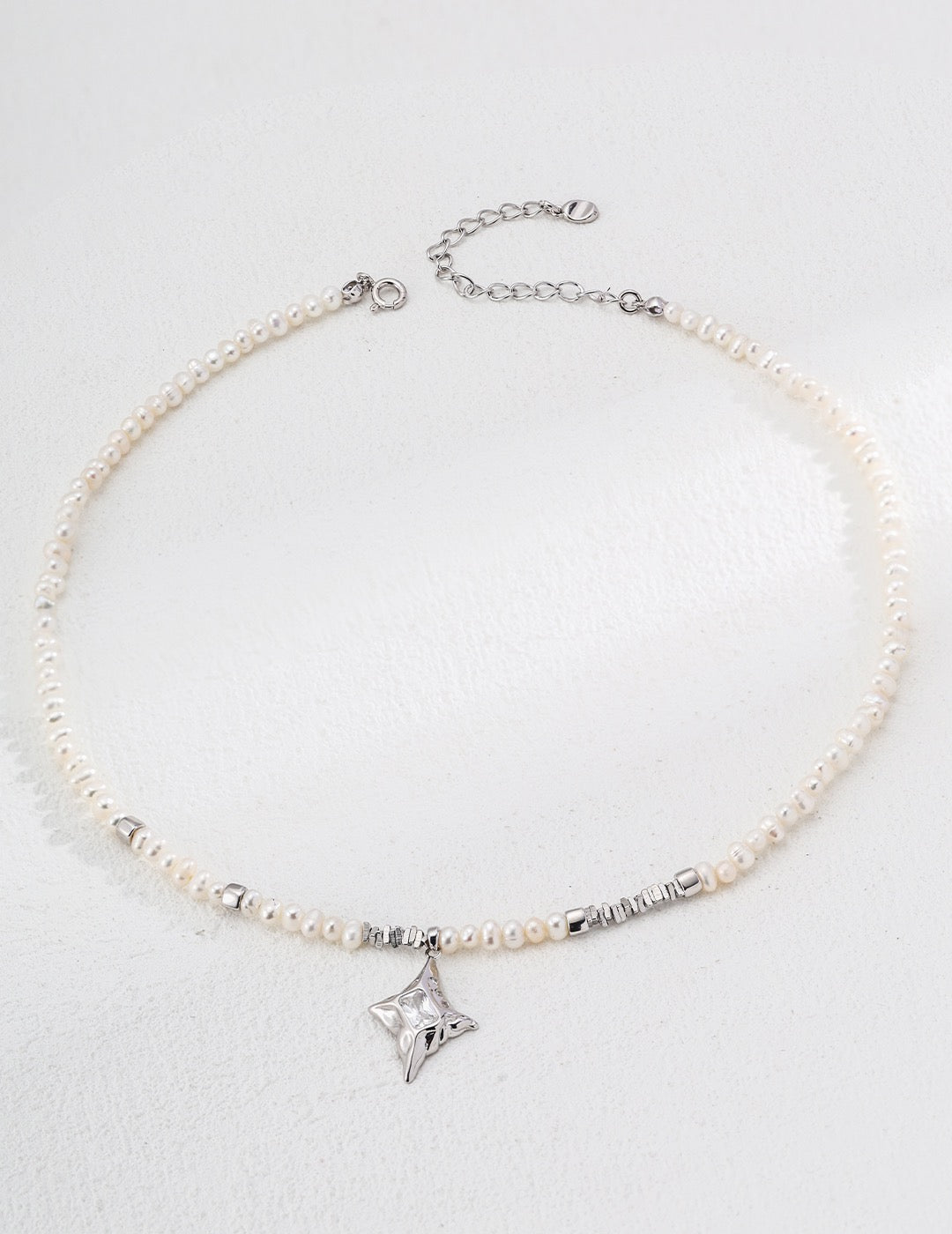 Pearl necklace with a star-shaped pendant on a light gray background
