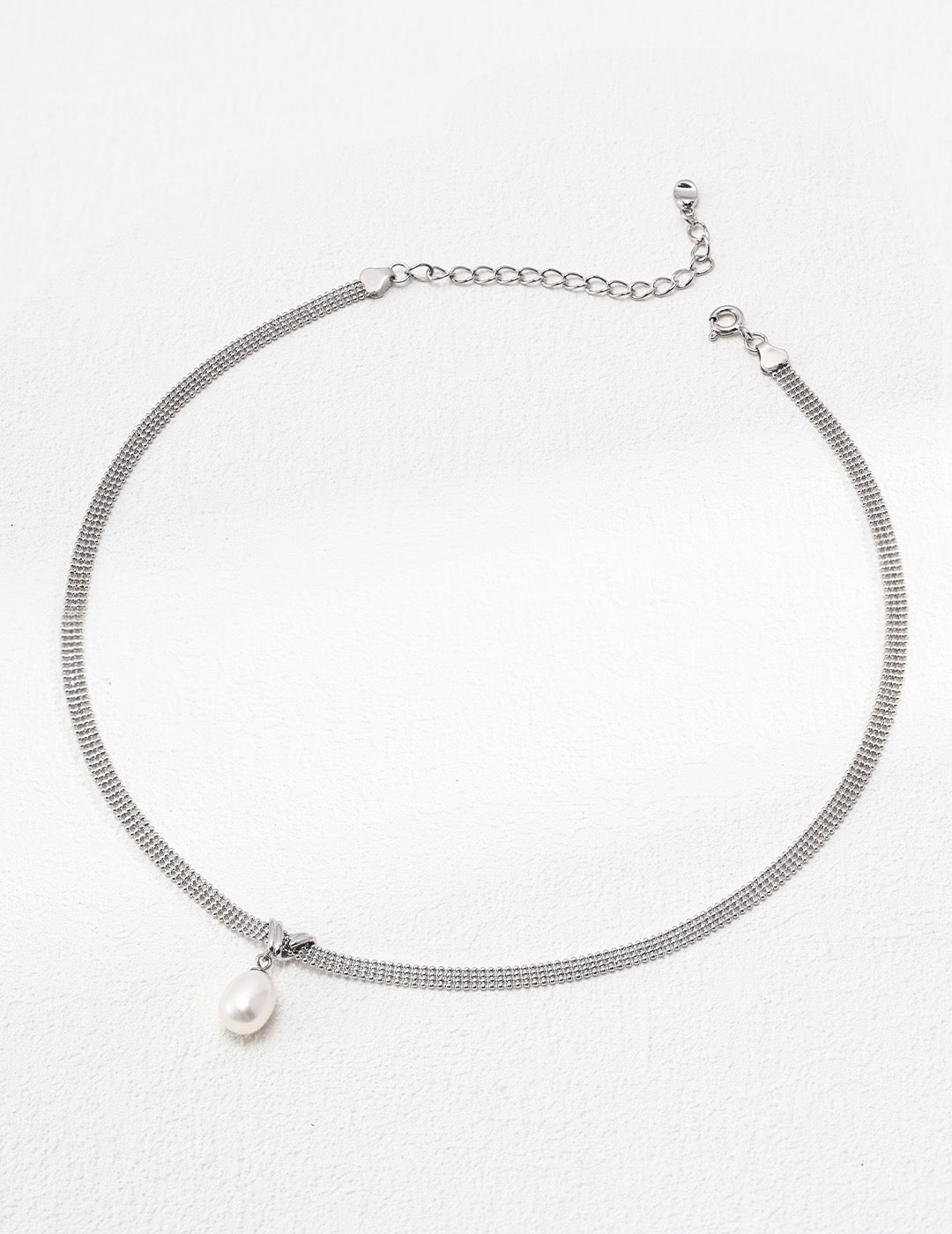 Silver necklace with a pearl pendant on a white background