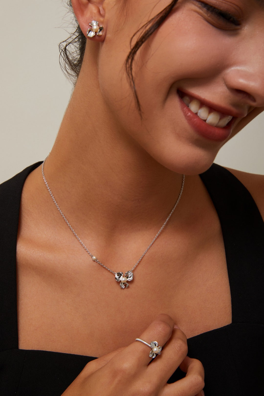 Woman wearing a silver necklace and earrings with a neutral background