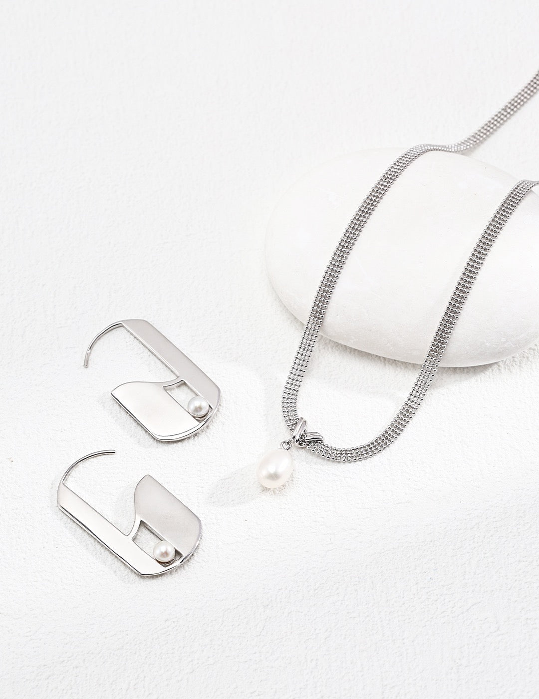 Silver necklace with a pearl pendant on a white background