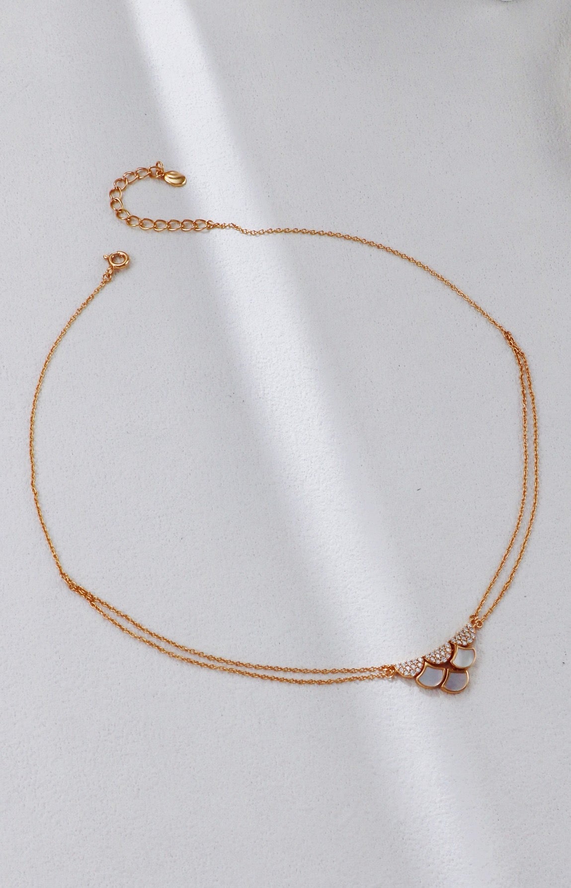 Rose gold necklace with heart-shaped pendants on a white background