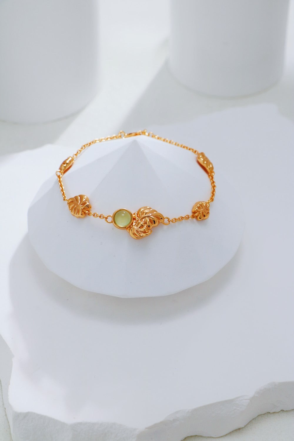 Gold bracelet with a green gemstone on a white mannequin bust.