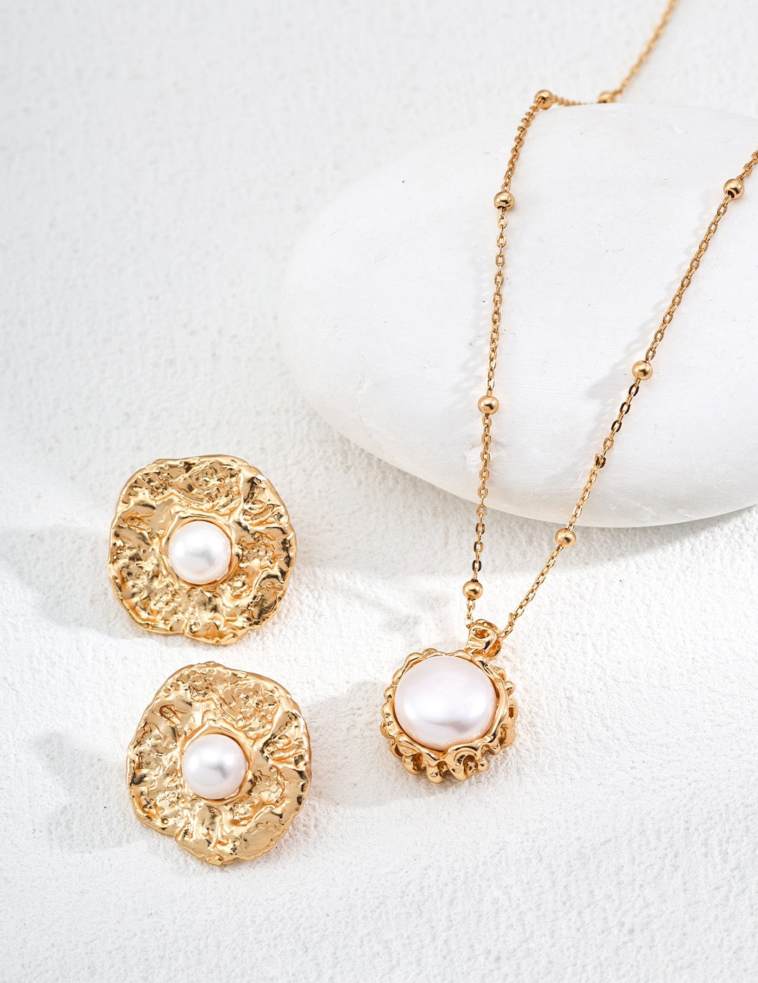 Gold necklace with pearl pendant on a white background