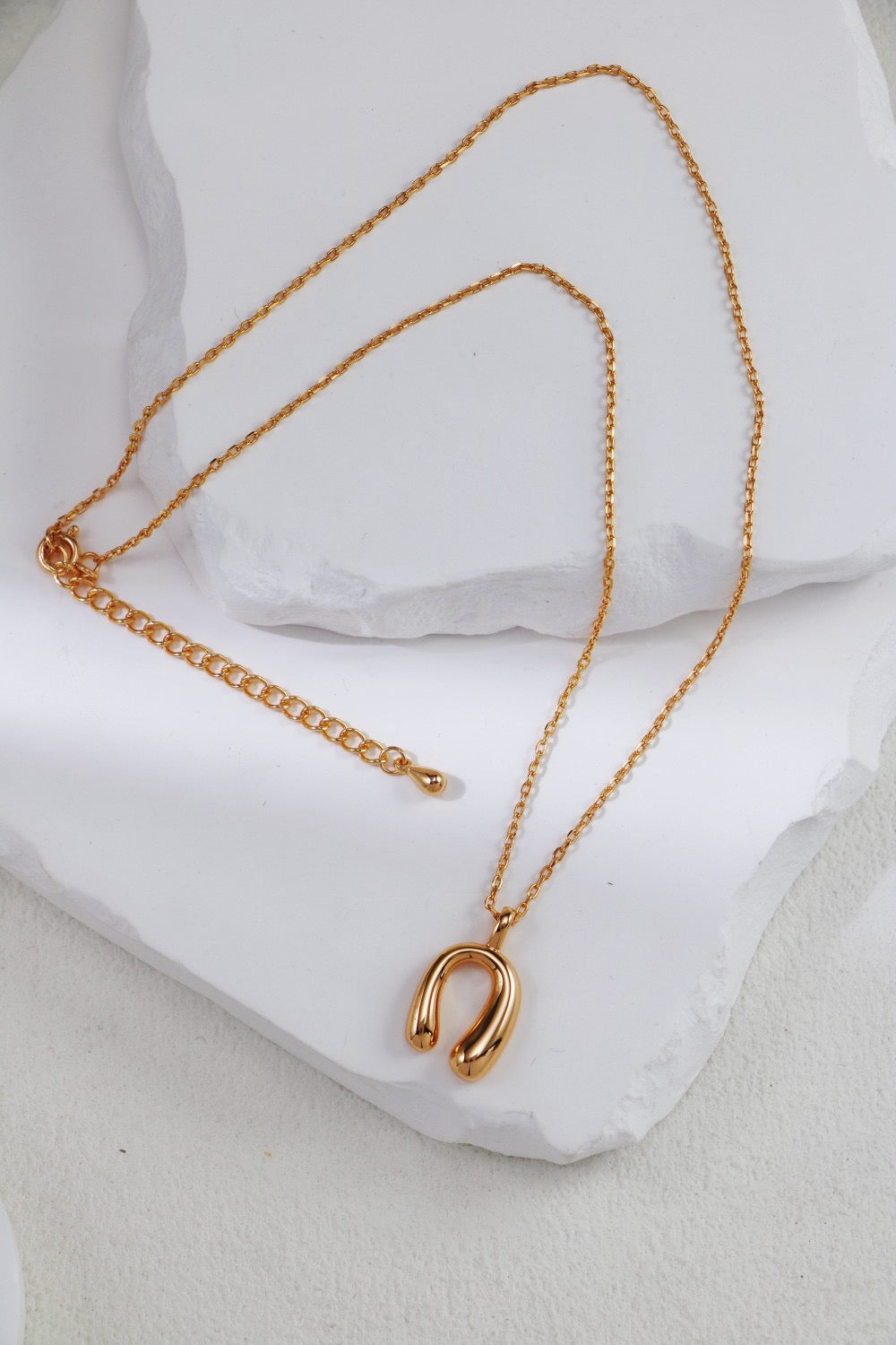Gold necklace with a horseshoe pendant on a white cushion