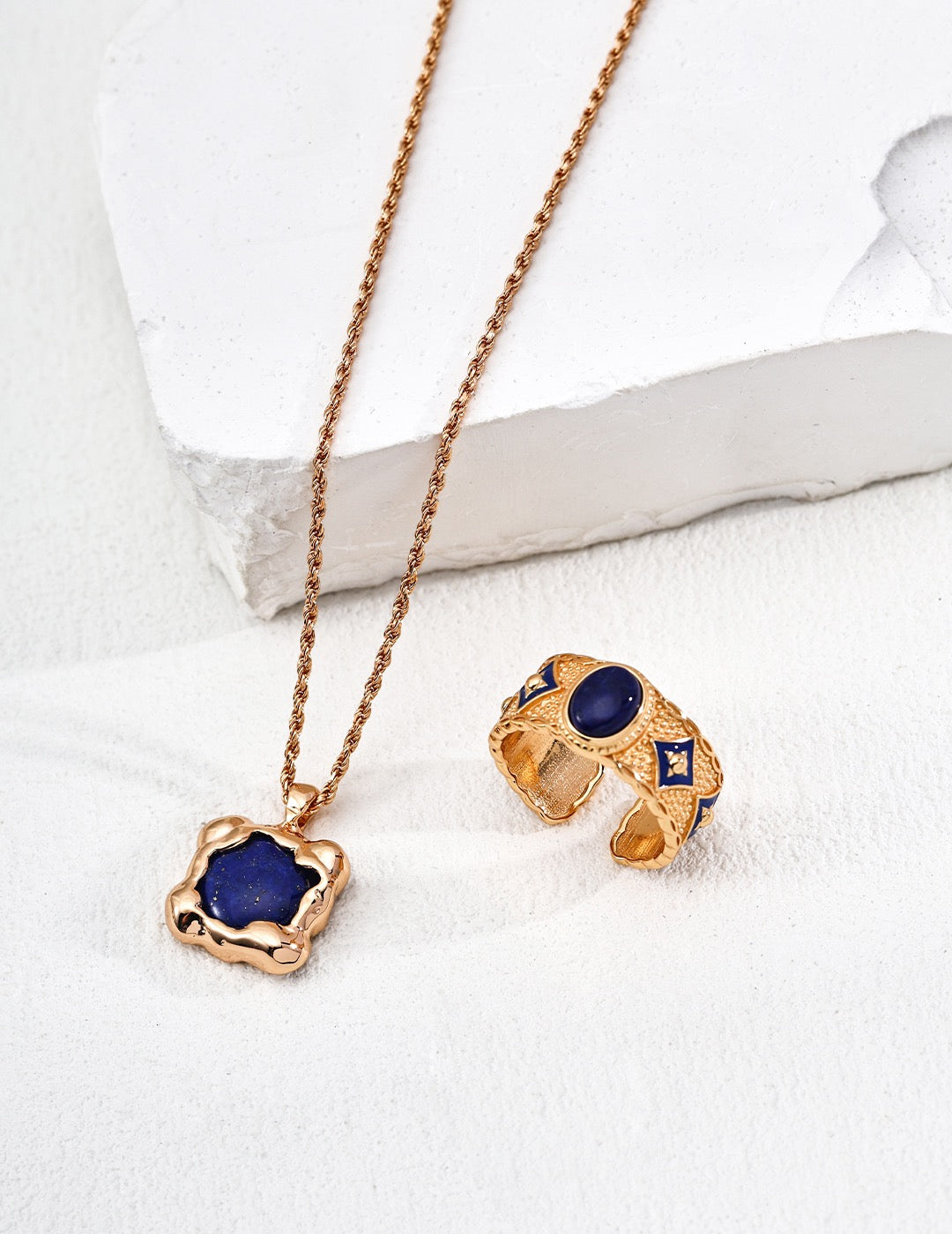Gold necklace and earrings with blue stones on a white background