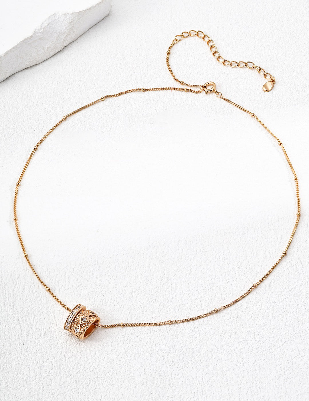 Rose gold necklace with a decorative clasp on a white background