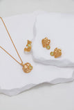 Gold jewelry set with leaf designs on a white fabric background