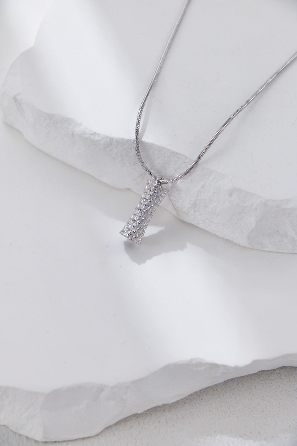 Silver necklace with a star-shaped pendant on a white fabric background