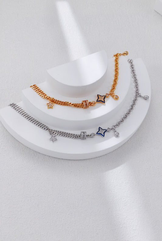 Three gold and silver bracelets with charms on a white stand.
