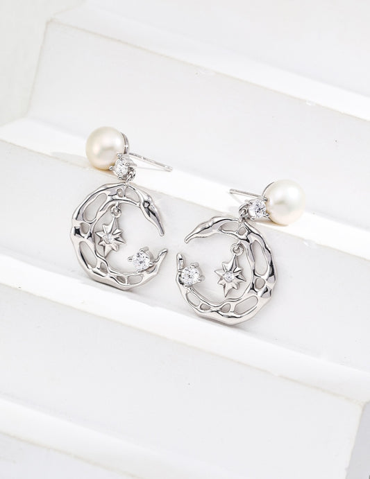 Silver earrings with moon and star designs on a white background