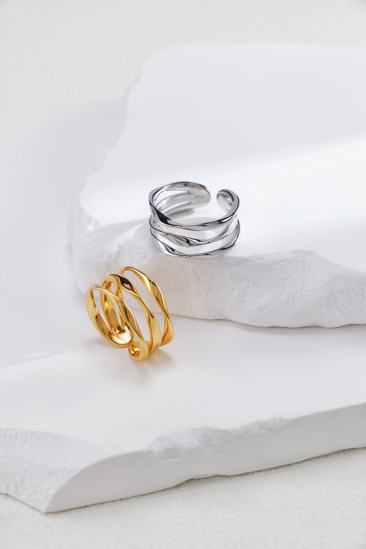 Two rings, one gold and one silver, on a white surface.
