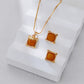 Gold necklace and earrings with amber-colored stones on a white surface
