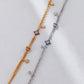 Two bracelets, one gold and one silver, with star-shaped charms on a light gray background.