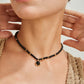 Close-up of a person wearing a black beaded necklace with a gold clasp.