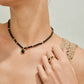 Woman wearing a black beaded necklace and ring with gold accents.