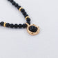 Black beaded necklace with a gold accent on a light gray background