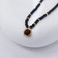 Necklace with black beads and a gold clasp on a white background