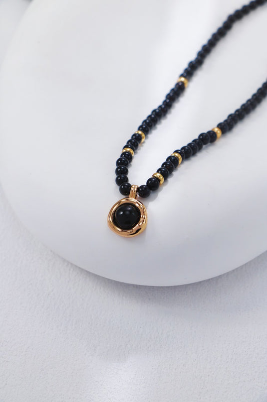 Necklace with black beads and a gold clasp on a white background