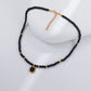Black beaded necklace with gold accents on a white stand