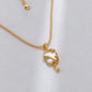 Gold necklace with a heart-shaped pendant on a light gray background
