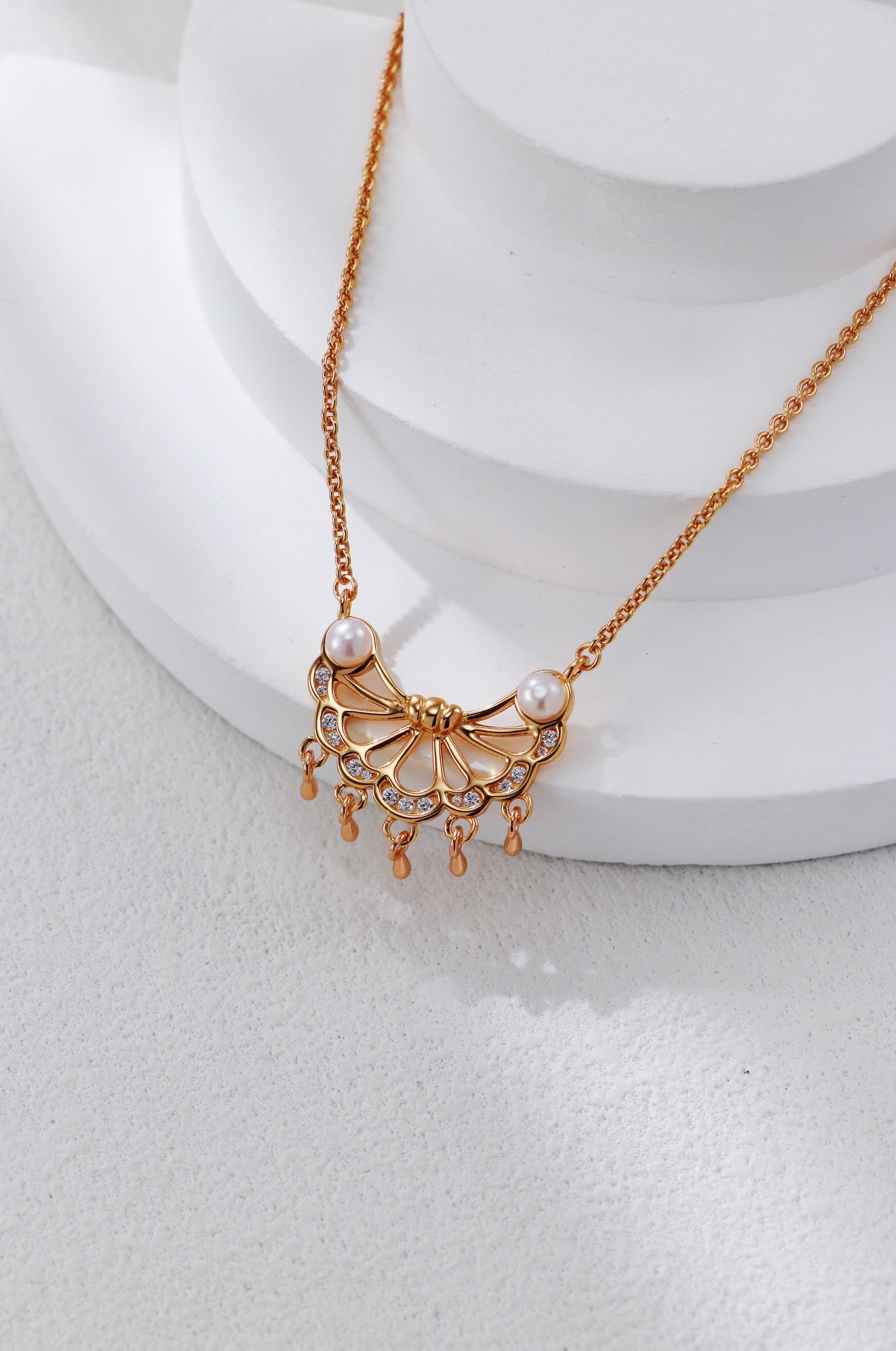 Gold necklace with a decorative pendant on a white surface