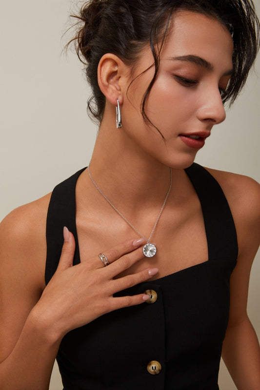 Woman wearing a black dress with jewelry including earrings, a necklace, and rings.