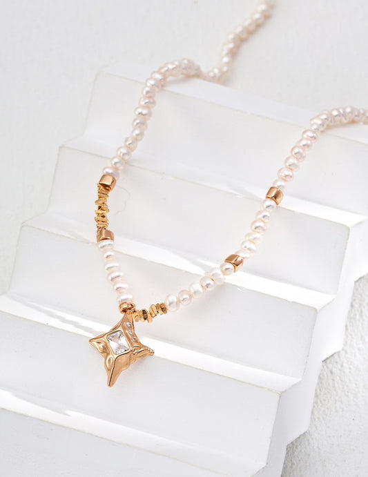 Pearl necklace with gold accents on a white stone surface