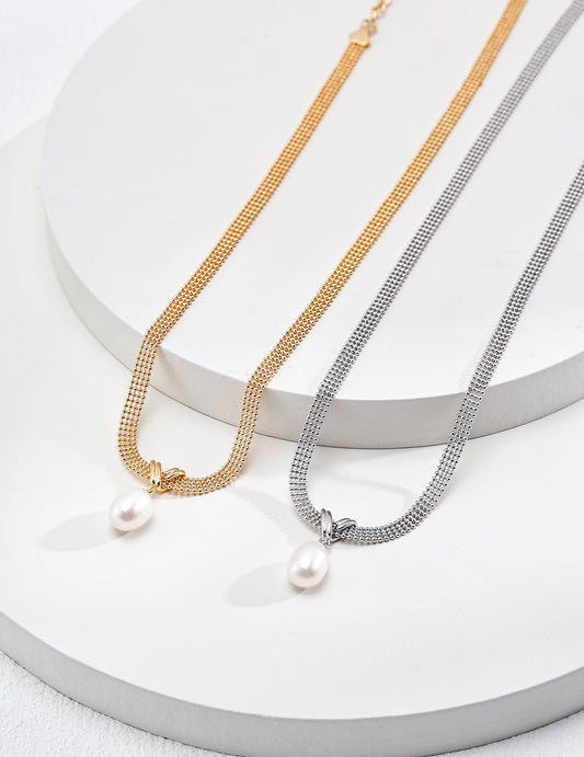 Two pearl necklaces on a white surface, one gold and one silver.
