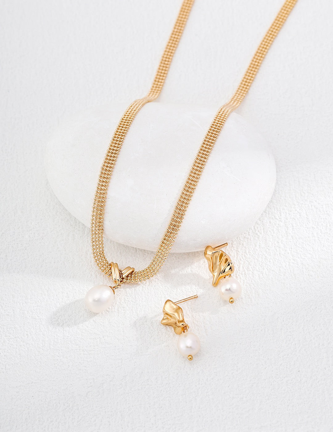Gold necklace and earrings set on a white background