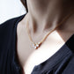 Close-up of a person wearing a delicate gold necklace with small stones.