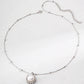 Silver anklet with a pearl charm on a light gray background
