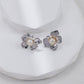 Pair of flower-shaped earrings with pearls on a white surface
