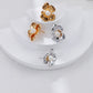 Set of gold and silver floral earrings on a white surface