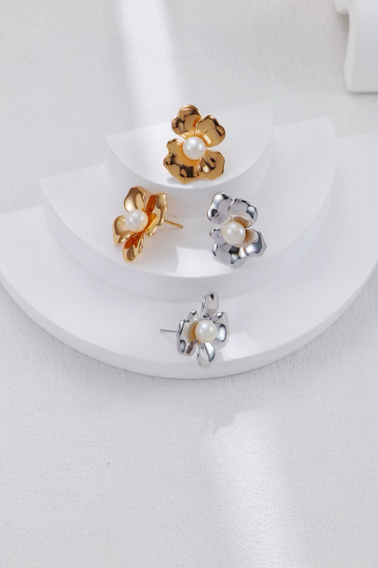 Set of gold and silver floral earrings on a white surface