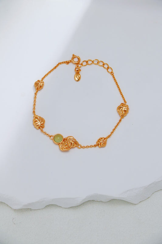 Gold bracelet with a green gemstone on a white fabric background