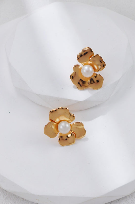 Gold flower-shaped earrings with pearl centers on a white background