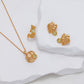 Gold jewelry set with leaf designs on a white fabric background