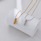 Two gold necklaces on a white stand against a light gray background