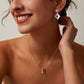 Woman wearing silver earrings and a necklace against a neutral background