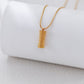 Gold necklace with a textured pendant on a white background