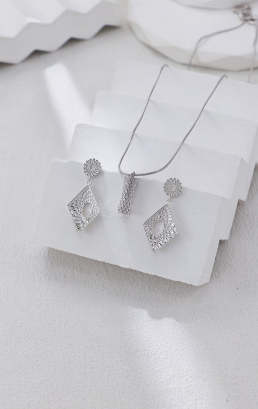 Silver jewelry set on a white fabric background
